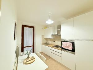 a white kitchen with a table and a refrigerator at LA Home - Animal House in Viareggio