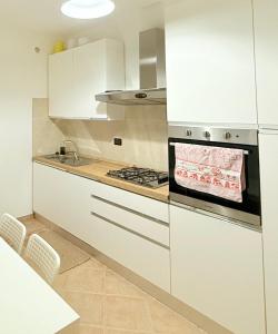a kitchen with white cabinets and a stove top oven at LA Home - Animal House in Viareggio +31 photos