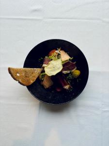 a black bowl of food with a wooden spoon at La Cremaillere Hôtel-Restaurant in Courseulles-sur-Mer