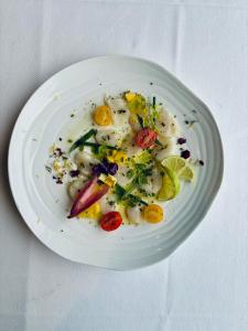 a white plate of food with vegetables on a table at La Cremaillere Hôtel-Restaurant in Courseulles-sur-Mer
