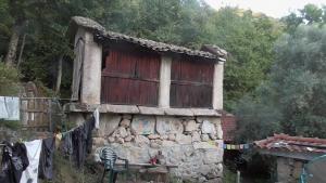 an old stone house with a window and a clothes line at Ecoaldea Vegetariana y Vegana Espiral in Cabeceiras de Basto
