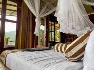 a bedroom with a bed with curtains and a window at Rustic Cottage in Ella