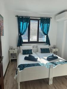 Dos camas en un dormitorio con cortinas azules. en Апартамент Слънчев дом, en Smolyan