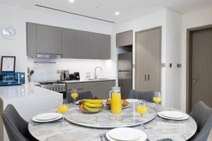 un tavolo con una ciotola di banane e bicchieri di succo d'arancia di EMAAR GRANDE - Elegant 1 Bedroom Apartment - Infinity Pool - 1min to Dubai Mall and Burj Khalifa a Dubai