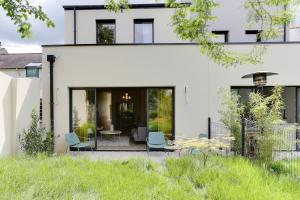 une maison blanche dotée d'une cour avec des chaises dans l'établissement Maison Joseph - Chambre 2, à Saint-Jacques-de-la-Lande