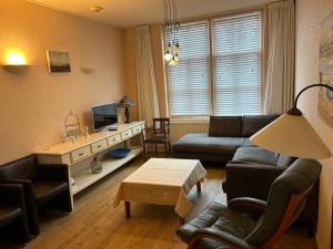 een woonkamer met een bank en een tv bij Voorstraat 30 Appartement in Colijnsplaat