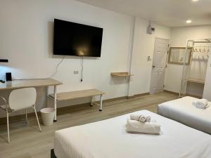 a room with two beds and a desk and a tv at Silpasala StayZ in Sathani Ban Hua Mak