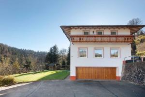 ein großes weißes Haus mit einer Holzgarage in der Unterkunft Apartment Todtmoos 3 in Todtmoos