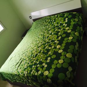 Una cama con un edredón verde encima. en Alcudia Smir, en Fnidek