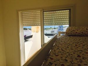 a bedroom with a window with a bed and a balcony at Alcudia Smir in Fnidek