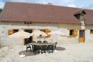 a table and chairs with umbrellas in front of a building at Le Coin des Hortensias in La Puye