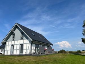 a white barn with a black roof on a grass field at Słowiński Horyzont in Rowy +15 photos