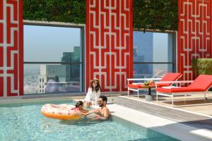 kobieta i dwie osoby w basenie w obiekcie Dusit Doha Hotel w mieście Doha
