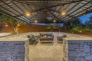 DebāriELIVAAS Cows & Cuddles 4 BHK with Pvt Pool and Garden的凉亭下有桌椅的露台