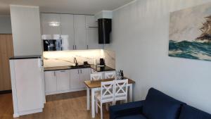 a small kitchen with a table and a blue couch at APARTAMENT BALTICHOFF FUN with Sea View, Basen, Spa, Gym, Sauna, Hala sportowa z kortem tenisowym in Gąski