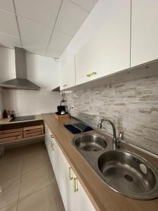a kitchen with a stainless steel sink and white cabinets at El cobijo in Granada