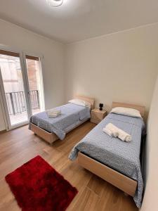 a bedroom with two beds and a red rug at Levante in Augusta
