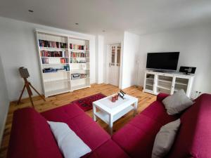 Una sala de estar con un sofá rojo y un televisor. en Haus Rosalinde, en Klüsserath