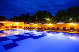 uma piscina com cadeiras e guarda-sóis à noite em Hotel Fazenda Areia que Canta em Brotas