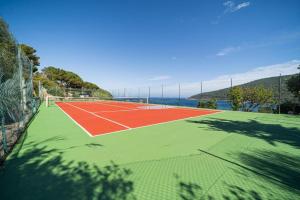 a tennis court with the ocean in the background at Villa Ray Beach in Capoliveri +27 photos
