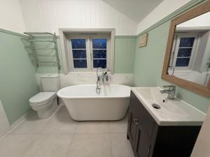 a bathroom with a tub and a toilet and a sink at Rose Cottage, Luxury cottage, sleeps 16 in South Raynham +40 photos