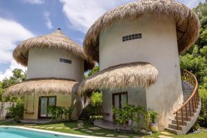 a house with two thatched huts next to a pool at Mimpi Tropis in Uluwatu