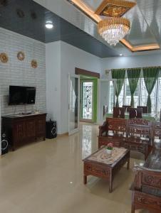 Una sala de estar con sofás, un televisor y una mesa. en Villa Highland No 8 UU Berastagi View, en Berastagi