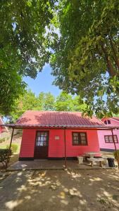 a red building with a red roof and a bench at kkcc แก่งกระจานแคมป์ - ริมน้ำ รีสอร์ต in Kaeng Krachan