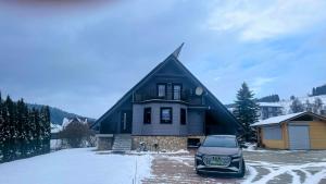 a car parked in front of a house in the snow at Skandynawski domek in Tylicz