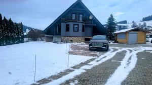 a car parked in front of a house in the snow at Skandynawski domek in Tylicz