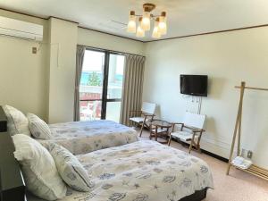 a hotel room with two beds and a tv at ビーチサイドペンションみーばる in Nanjo +9 photos