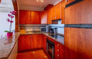 a kitchen with wooden cabinets and a sink at Cozy Apartment In Cumbre Del Sol in Cumbre del Sol +24 photos