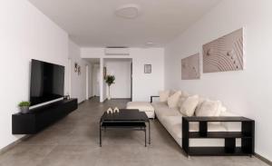 a living room with a white couch and a tv at Stunning and spacious in Kiryat Ata in Qiryat Ata