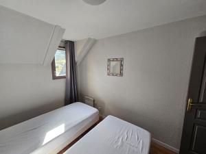 two beds in a small room with a window at La Mongie Appartement duplex 2 à 7 personnes in Bagnères-de-Bigorre +25 photos