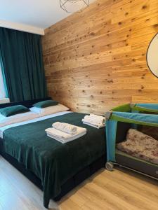 two beds in a room with wooden walls at Green Loft Apartament in Biała Podlaska