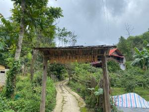 un puente de madera con un camino de tierra en un campo en Homestay Loan Ươi, en Bắc Hà
