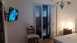 ein Zimmer mit Fernseher, Stuhl und Fenster in der Unterkunft Residence Ginevra-Porto Miggiano in Santa Cesarea Terme