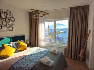 a bedroom with a bed and a large window at Mountain and City View with Underground Parking in Braşov