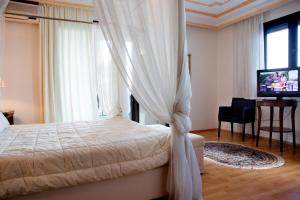 a bedroom with a bed with curtains and a television at Kymata Hotel in Platamonas
