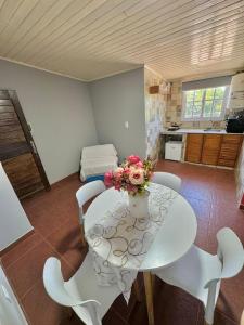 ein weißer Tisch und Stühle mit einer Blumenvase drauf in der Unterkunft Departamento pequeño en gobernador roca in Gobernador Roca