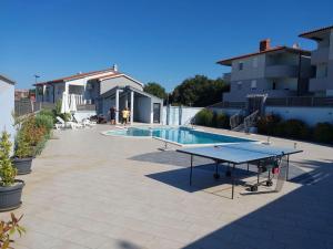 a ping pong table on a patio next to a pool at Apartment Tina in Vodnjan
