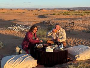 a man and a woman sitting at a table in the desert at Bivouac La Dune Blanche in Mhamid