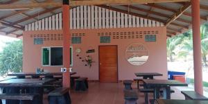 a restaurant with wooden tables and benches and a door at ปุณยวีร์โฮมสเตย์ in Koh Phaluai