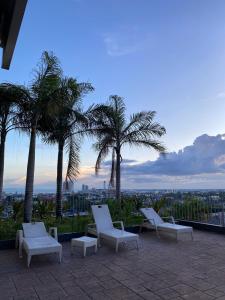 a group of white chairs sitting on a patio with palm trees at Twilight25 Condo in Cebu City