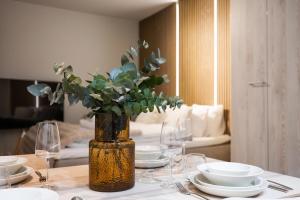 a table with plates and glasses and a vase with a plant at Arctic Honey City Suite in Rovaniemi +10 photos
