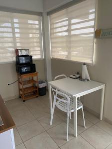 une table et une chaise blanches dans une pièce avec des fenêtres dans l'établissement Apartamento karma, à Culebra