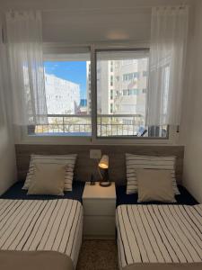 two beds in a room with two windows at SOLMAR Playa Gandia SOLO FAMILIAS in Playa de Gandia
