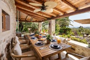 an outdoor dining room with a wooden table and chairs at Corfu OliveStone Village with Swimming pool in Ágios Márkos