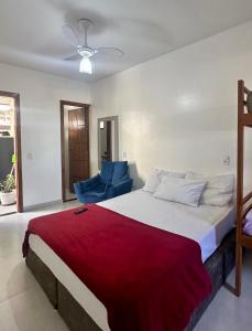 een slaapkamer met een groot bed en een blauwe stoel bij Âncora Lofts in Arraial do Cabo