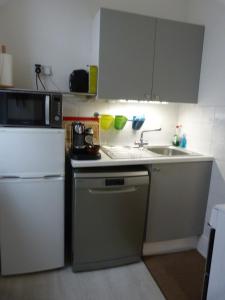 a kitchen with a sink and a microwave and a refrigerator at Wee Ness Cottage in Inverness